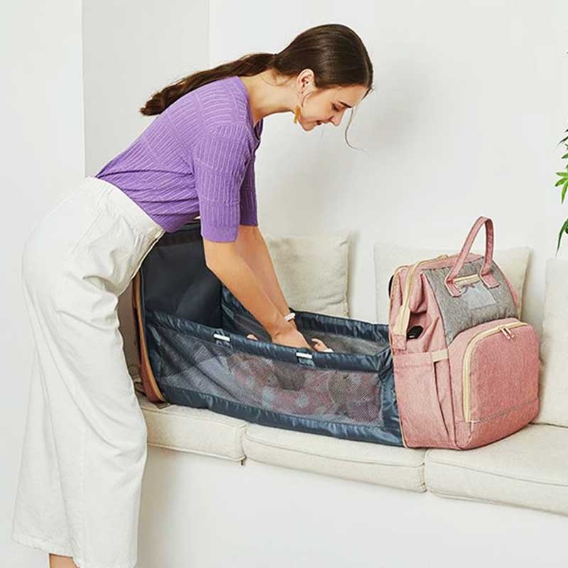 Une maman change son bébé dans le lit intégéré au sac a langer lit